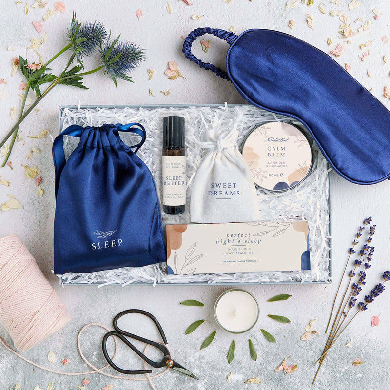 A  letterbox-friendly sleep gift set containing a blue silk eye mask and skincare products wrapped in paper straw